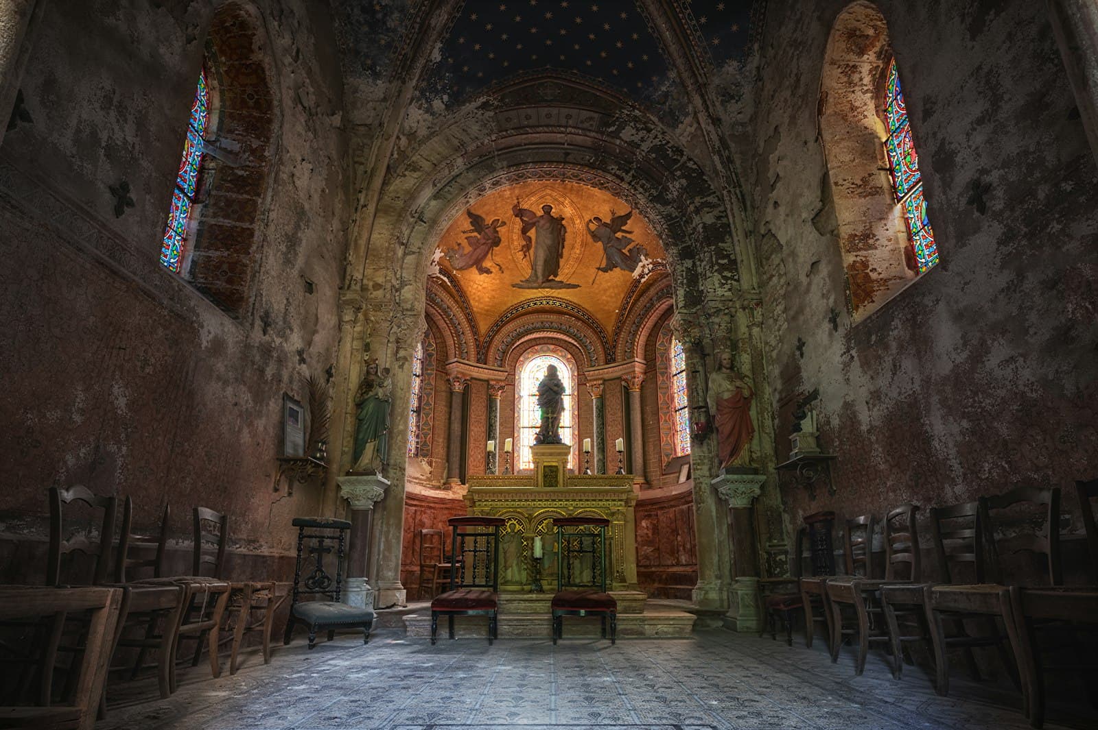 An ornate, aged chapel interior with stained glass windows
